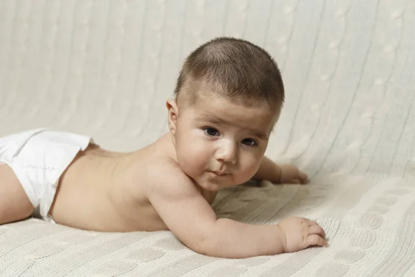 4 aylık bir erkek bebek karnı üzerinde evde yatıyor