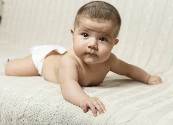 4 aylık bir erkek bebek karnı üzerinde evde yatıyor