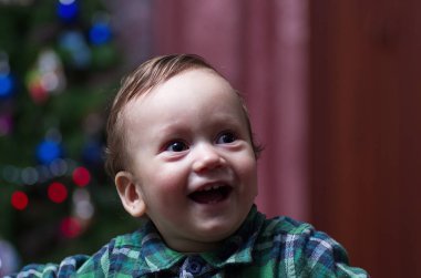 Küçük bir çocuk Noel ağacında duruyor..