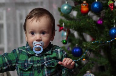 Küçük bir çocuk Noel ağacında duruyor..