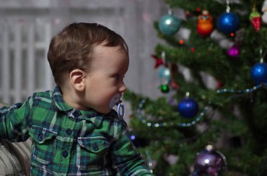 Küçük bir çocuk Noel ağacında duruyor..