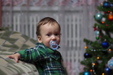 Küçük bir çocuk Noel ağacında duruyor..