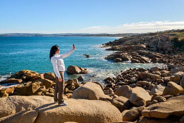 Woman taking selfie with mobile phone on the sea shore 