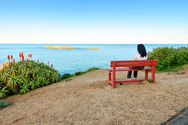 Žena sedí na lavičce s výhledem na moře — Stock fotografie