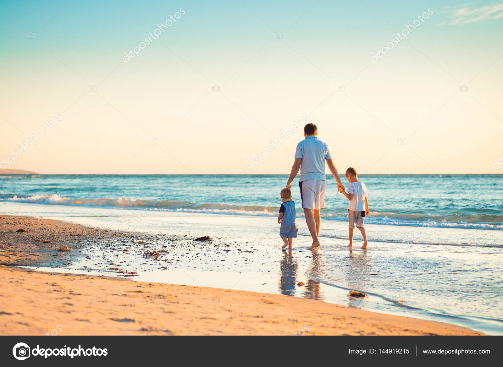 Familia feliz con dos niños caminando en la playa del 