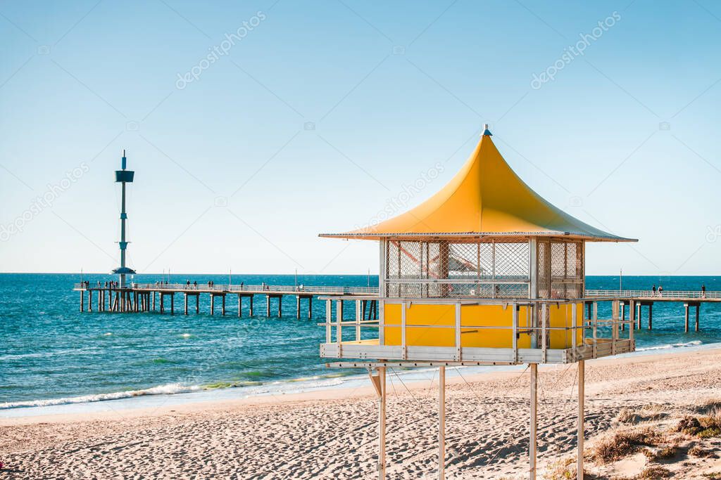 Brighton surf life saving tower with people walking along the jetty on the background, South Australia