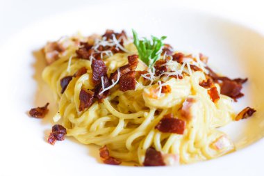 Spagetti Carbonara 'yı pastırma ve peynirli beyaz tabakla kapat.