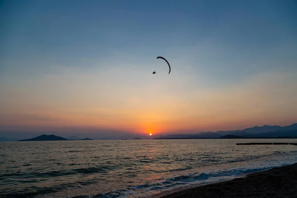 Günbatımında Ege Denizi 'ndeki Calis Sahili' nde sahil üzerinde bir paraglider.