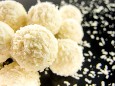 Siyah arka planda Hindistan cevizi taneleri olan lezzetli beyaz çikolata topları.