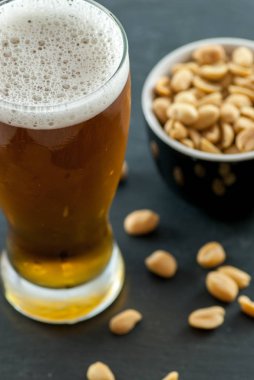 Kavrulmuş ve tuzlanmış fıstıklı bir bardak bira ve kase.