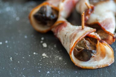 Lezzetli domuz pastırması sarılı tavuk ciğeri, siyah üzerine tuz ve fotokopi alanı.