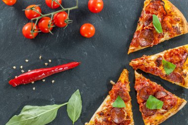 Lezzetli taze biberli pizza dilimleri kiraz domatesli kırmızı biber ve fesleğen yapraklı.