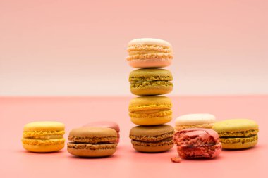 delicious various macarons stacked and some spread around on warm colored background