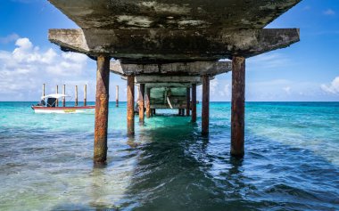 Güzel mavi sularda, küçük bir teknenin yanındaki eski bir rıhtımın alt manzarası.