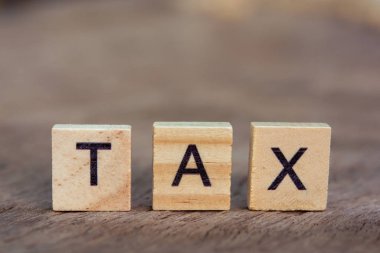 Tax with wooden alphabet blocks, on plank wooden background with