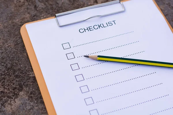 Checklist concept - checklist, paper and a pen with checklist word on wooden table