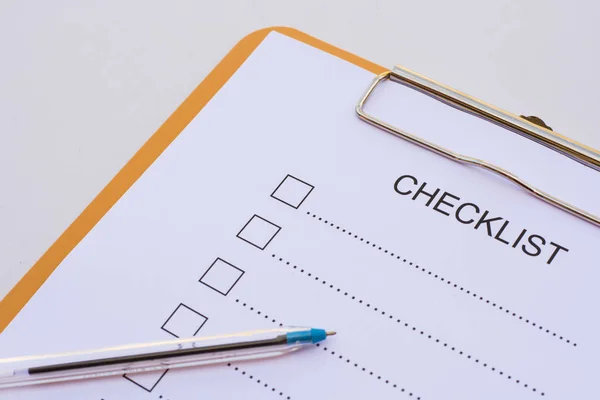 Checklist concept - checklist, paper and a pen with checklist word on wooden table