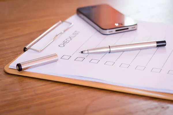 チェックリストの概念 チェックリスト 紙と木製のテーブル上のチェックリストの単語を持つペン — ストック写真