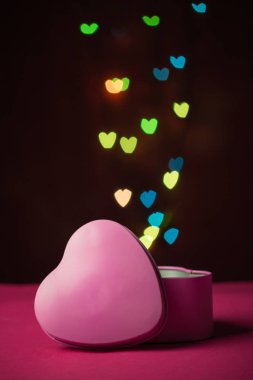 Pembe hediye kutusu. Açık kalp. Odaklanmamış bokeh renkli ışıklar, kalp şeklinde arka plan.