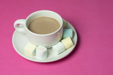 hot chocolate with marshmallows in a ceramic cup on pink paper background