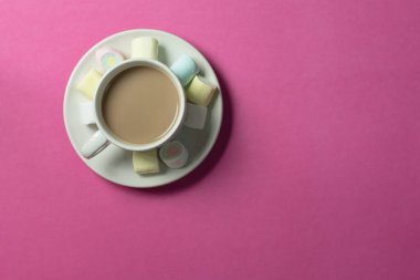 hot chocolate with marshmallows in a ceramic cup on pink paper background