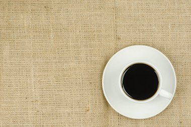 White cup with coffee drink on sackcloth background