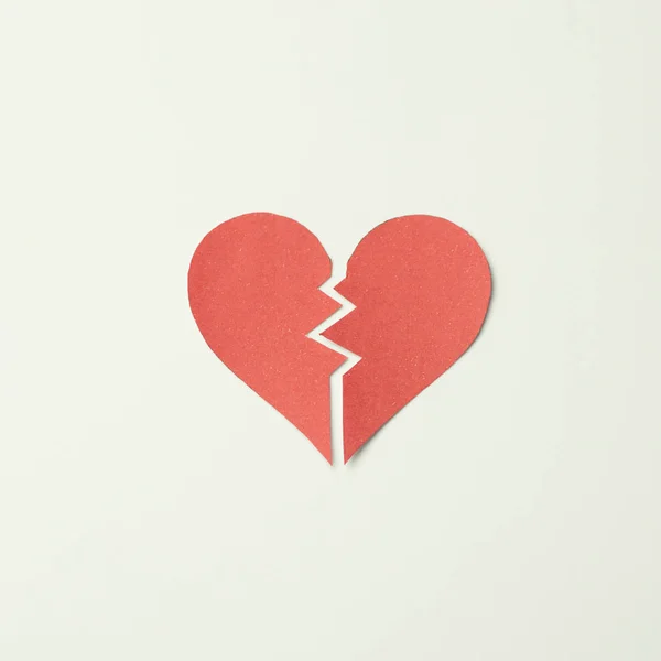 Red paper broken heart on white background