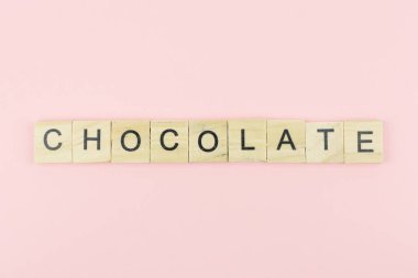 Metin tahta bloklar pembe arka planda çikolata kelimesini heceliyor