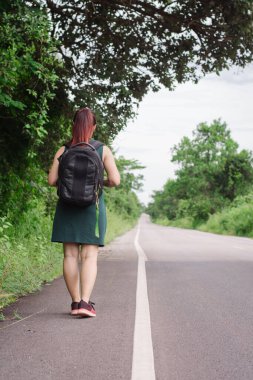 Yol ve orman arka plan, tatil kavramı seyahat zamanında Relax mutlu Asyalı kız sırt çantası