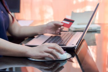 Kredi kartı tutan ve dizüstü bilgisayar kullanan bir kadın. Çevrimiçi alışveriş kavramı