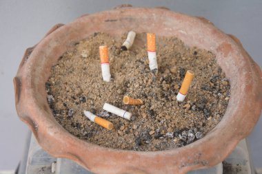 Sigaraların geri kalanı kül tablasında. Kül tablasında kumun üzerinde bir sürü sigara izmariti vardır..