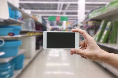 hand holding mobile smart phone with blank monitor screen on Supermarket blur background, business concept