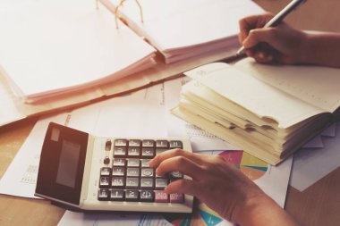 Kadın eli hesap makinesi ve yazma kullanıyor. Hesaplı, iş konseptiyle not alın.