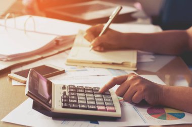 Kadın eli hesap makinesi ve yazma kullanıyor. Hesaplı, iş konseptiyle not alın.