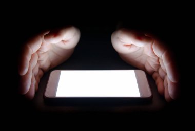 Akıllı telefondan gelen beyaz ışık gece karanlığında elinizi yansıtır. Metin ve tasarım için boş ekran