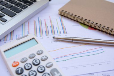 Ofis kavramları: hesap makinesi, dizüstü bilgisayar, defter ve kalemle analiz edilen veriler. Sonuçları bulmak için grafikler ve grafikler üzerinde.