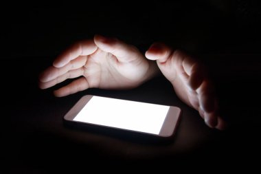 Akıllı telefondan gelen beyaz ışık gece karanlığında elinizi yansıtır. Metin ve tasarım için boş ekran