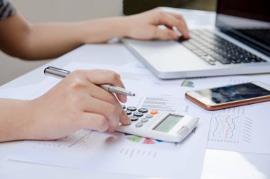 hesap makinesi ve dizüstü ekonomi ofisinde yapmakla kağıt grafik verilerini kullanarak kadın kapatmak.