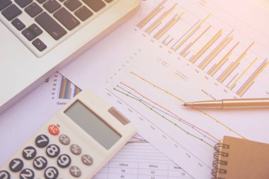 Ofis kavramları: hesap makinesi, dizüstü bilgisayar, defter ve kalemle analiz edilen veriler. Sonuçları bulmak için grafikler ve grafikler üzerinde.