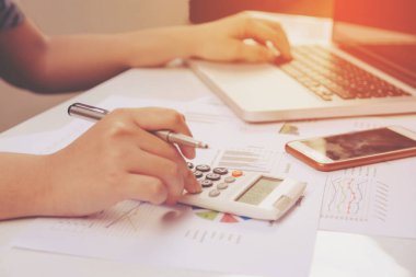 hesap makinesi ve dizüstü ekonomi ofisinde yapmakla kağıt grafik verilerini kullanarak kadın kapatmak.