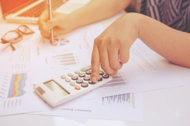 Kağıt grafik verileri üzerinde hesap makinesi kullanarak ofis finansmanı yapan kadını kapat.