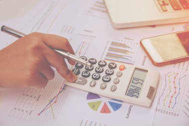 Kağıt grafik verileri üzerinde hesap makinesi kullanarak ofis finansmanı yapan kadını kapat.