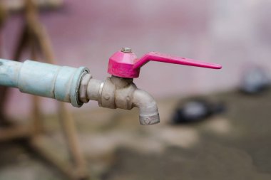 Bulanık bir arka plan üzerinde damlayan eski musluk suyu