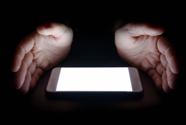 Akıllı telefondan gelen beyaz ışık gece karanlığında elinizi yansıtır. Metin ve tasarım için boş ekran