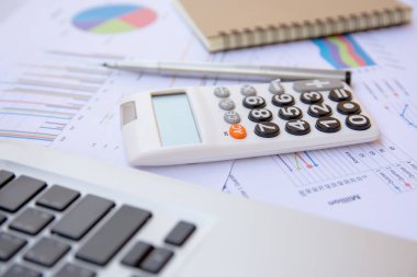 Ofis kavramları: hesap makinesi, dizüstü bilgisayar, defter ve kalemle analiz edilen veriler. Sonuçları bulmak için grafikler ve grafikler üzerinde.