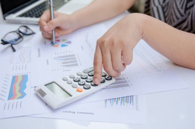 Kağıt grafik verileri üzerinde hesap makinesi kullanarak ofis finansmanı yapan kadını kapat.