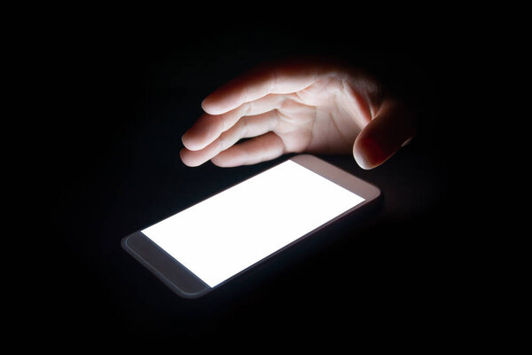 white light from the smartphone reflect your hand at night in the dark.blank screen for text and design