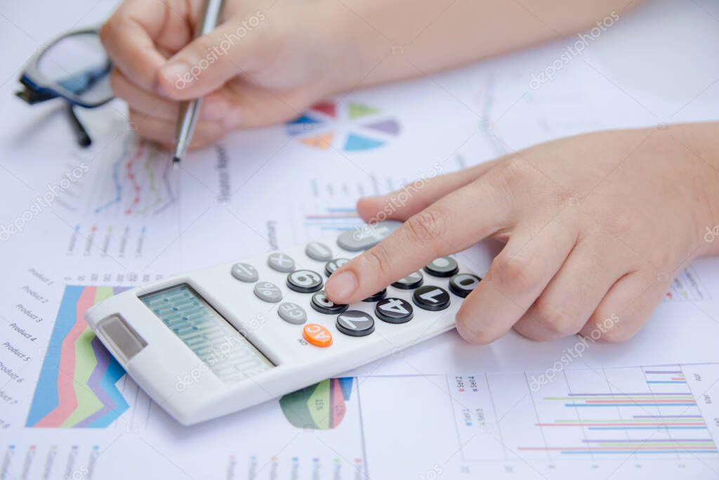close up woman using calculator on paper graph data with doing finance at office.