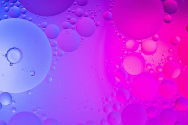 Su yüzeyi renk arkaplanına yağ damlaları düşer. mavi ve pembe daireler 