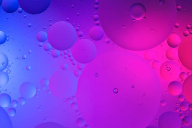 Su yüzeyi renk arkaplanına yağ damlaları düşer. mavi ve pembe daireler 